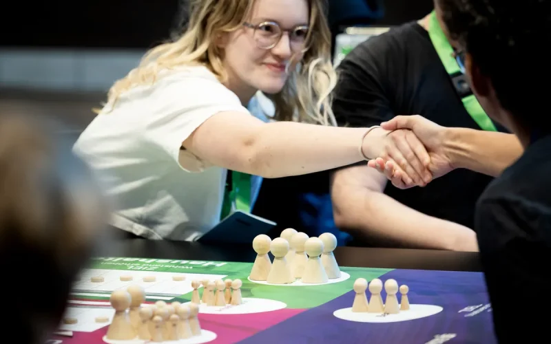 Personen reichen sich die Hand am Spieltisch Personen reichen sich die Hand am Spieltisch
